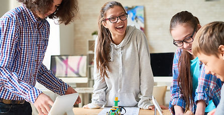 Teenagers standing around table with Lego robot.