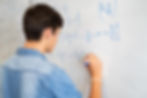 A teenager solving mathematical rational equation by the whiteboard.