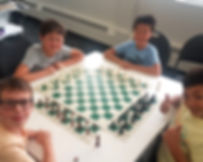 Desk with chess board and children playing chess at Flying Minds education centre chess club