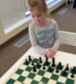 Desk with chess board and a child analyzing the chess puzzle at Flying Minds education centre chess club