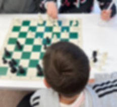Desk with chess board and children playing chess at Flying Minds education centre chess club