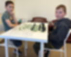 Desk with chess board and children playing chess at Flying Minds education centre chess club